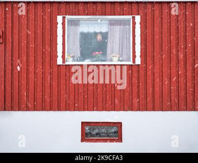 Esterno di parete rossa di legno duro e cornice finestra di pesca casa nordica nella stagione invernale nelle isole Lofoten Foto Stock