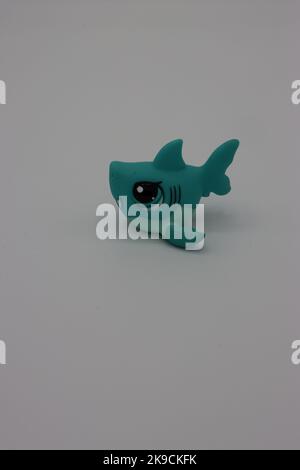 Piccolo, carino squalo di plastica figura animale su uno sfondo bianco. Cucciolo isolato più piccolo con testa grande e occhi grandi. Foto Stock