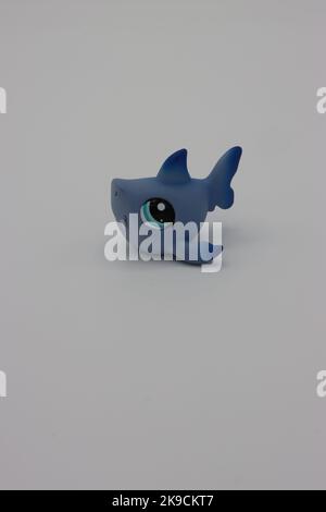 Piccolo, carino squalo di plastica figura animale su uno sfondo bianco. Cucciolo isolato più piccolo con testa grande e occhi grandi. Foto Stock