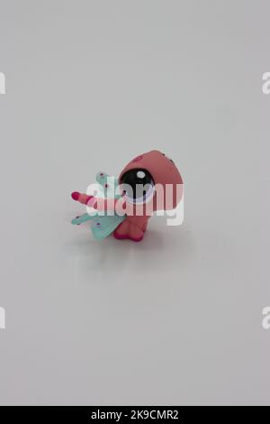 Piccola, carina figura animale di libellula di plastica su uno sfondo bianco. Piccolo cucciolo isolato da collezione con testa e occhi grandi. Foto Stock