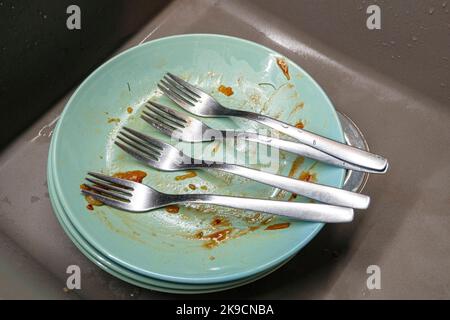 Piastre sporche con quattro forcelle in un lavello da cucina, vista dall'alto Foto Stock