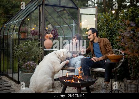 Giovane coppia e cane vicino al fuoco sul cortile Foto Stock