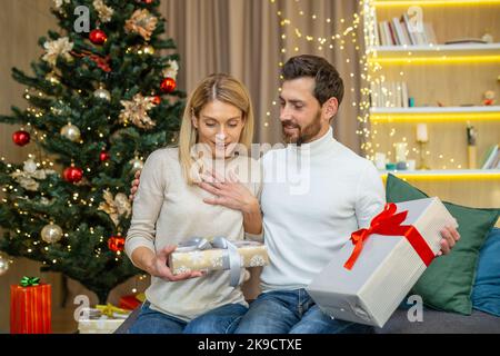 Coppia di mezza età che si scambiano i regali per natale, famiglia innamorata per natale a casa seduta sul divano a casa. Foto Stock