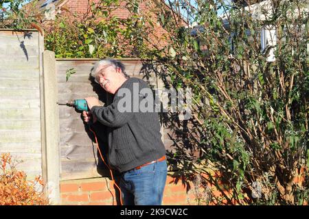 Uomo che utilizza un trapano elettrico. Indossare protezioni per gli occhi. Mendendo una recinzione. Foto Stock