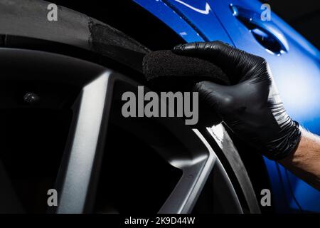 Annerimento della ruota di pneumatico di automobile usando la spugna con annerimento chimico della gomma nel servizio auto di dettaglio Foto Stock