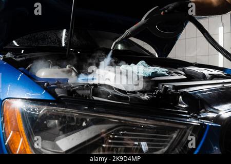 Lavaggio a vapore del motore di auto nei dettagli del servizio auto. Processo di pulizia a vapore del motore dell'auto da polvere e sporcizia Foto Stock