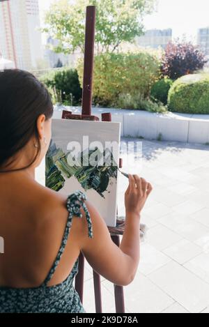 Giovane artista donna dipinge con una spatola sulla tela Foto Stock