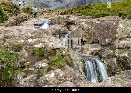 Isola di Skye, Scozia, Regno Unito-27 2022 luglio: Turisti che visitano la bella e popolare zona di cascate, arrampicata tra i massi, nuoto Foto Stock