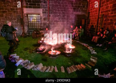 Paisley, Scozia, Regno Unito. 27th ottobre 2022. Le persone che si siedono intorno al Creepy Campfire ascoltando le storie di Halloween dei tempi antichi accanto all'Abbazia di Paisley durante il Paisley Halloween Festival. Credit: SKULLY/Alamy Live News Foto Stock