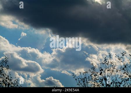 Immagine statica dell'elicottero scuro che vola sopra la testa con cielo nuvoloso blu sullo sfondo. Foto Stock