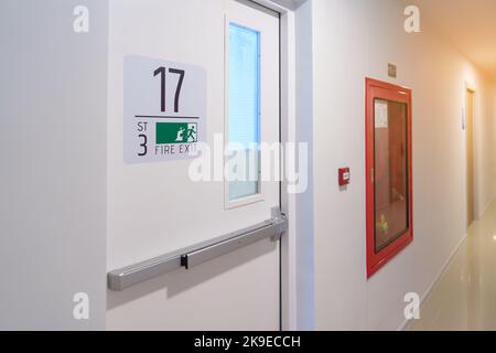 Sistema di estintore a parete con segnale di emergenza per la porta di uscita antincendio. Scalinata fuoco per fuga in edificio o appartamento Foto Stock