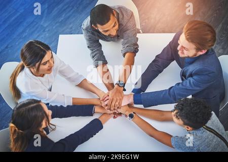 Con tutti noi lavorare insieme è stato destinato a successo. Colpo ad angolo alto di un gruppo di giovani uomini d'affari che uniscono le mani insieme in unità durante Foto Stock