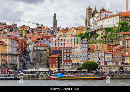 Facciate di tradizionali case portoghesi colorate a Ribeira e barche rabelo ormeggiate a Douro al tramonto Golden hour, Porto, Portogallo Foto Stock