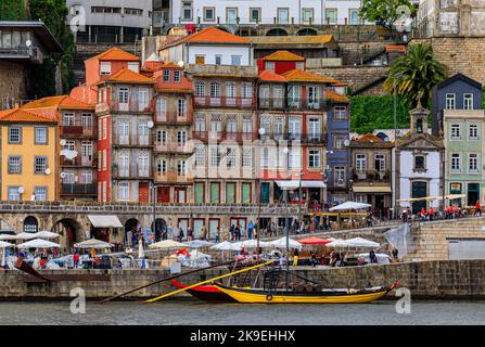 Facciate di tradizionali case portoghesi colorate a Ribeira e barche rabelo ormeggiate a Douro al tramonto Golden hour, Porto, Portogallo Foto Stock