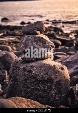 Pietre equilibrate l'una sull'altra per costruire un cairn alla spiaggia Foto Stock