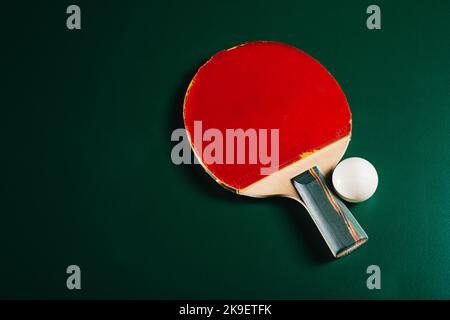 Racchetta da ping pong e una palla sono sdraiati su un tavolo da gioco verde Foto Stock