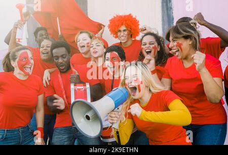 Gruppo di tifosi gioiosi e diversi che urlano durante la partita di calcio Foto Stock