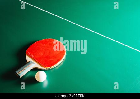 Racchetta da ping pong e una palla sono sdraiati su un tavolo da gioco verde Foto Stock