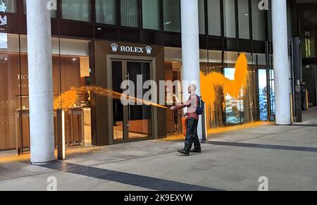 Foto dell'handout pubblicata da Just Stop Oil di uno dei loro attivisti che spruzzano vernice arancione sulle finestre dello showroom Rolex a Knigtsbridge, Londra. Data di emissione: Venerdì 28 ottobre 2022. Foto Stock