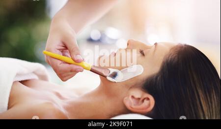Una pelle fantastica è a portata di viso, una giovane donna che riceve un trattamento viso in una spa. Foto Stock