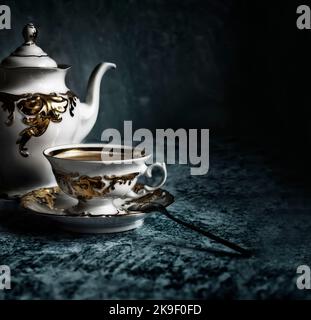 Raffinata tazza da caffè bianca e dorata su sfondo blu astratto. Caffè con un'appetitosa schiuma dorata. Foto Stock
