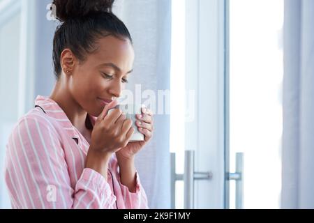 Questo odore e sapore così buono. Una giovane donna attraente godendo il suo caffè mattutino a casa. Foto Stock