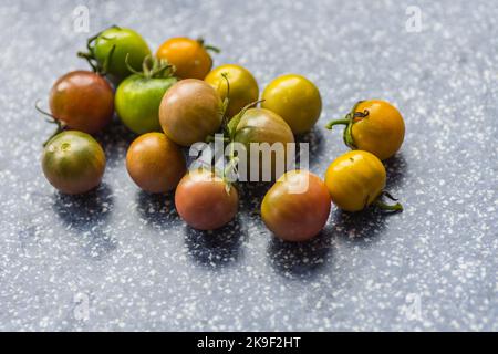 molti pomodori poco maturi con colori diversi in cucina Foto Stock