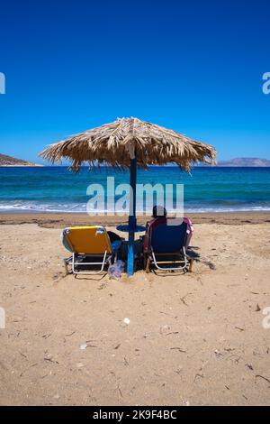 IOS, Grecia - 9 settembre 2022 : Vista di un turista che si rilassa su un lettino solare alla spiaggia stupefacente di Agia Theodoti in Grecia iOS Foto Stock