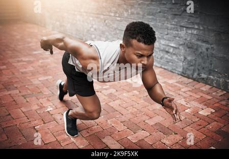 Siate determinati a raggiungere i vostri obiettivi di fitness. Un giovane sportivo che si esercita all'aperto. Foto Stock