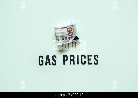 Prezzi del gas, concetto di crisi energetica. Aumento dei prezzi della benzina. Stack di fatture in dollari e testo prezzi del gas su sfondo blu Foto Stock