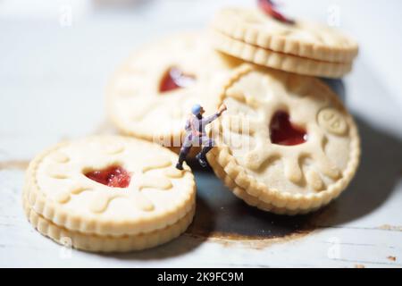 Uomini in miniatura e montagna biscotto, una serie di fotografie che utilizzano persone in miniatura, biscotti alla marmellata e ciottoli che mostrano un mondo di immagini in miniatura. Foto Stock