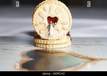 Uomini in miniatura e montagna biscotto, una serie di fotografie che utilizzano persone in miniatura, biscotti alla marmellata e ciottoli che mostrano un mondo di immagini in miniatura. Foto Stock