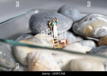 Uomini in miniatura e montagna biscotto, una serie di fotografie che utilizzano persone in miniatura, biscotti alla marmellata e ciottoli che mostrano un mondo di immagini in miniatura. Foto Stock