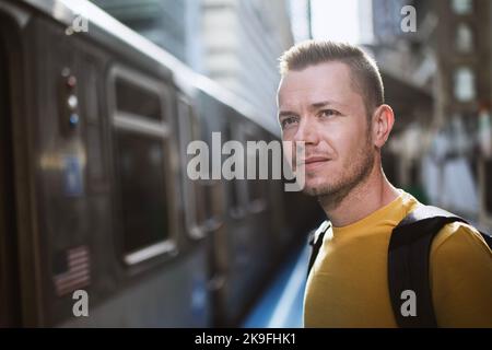Ritratto di uomo in attesa di pendolarismo treno di trasporto pubblico. Passeggero in piedi alla stazione della piattaforma. Foto Stock
