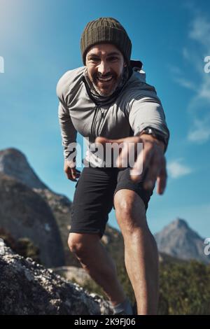 Prendi la mia mano e lascia andare oltre insieme. Basso ritratto angolato di un uomo di mezza età che raggiunge la mano mentre si fa trekking in montagna. Foto Stock