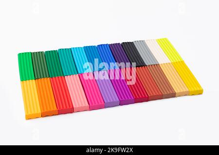 24 colori set di colorati bastoncini di plastilina isolati su sfondo bianco. Pezzi di plastilina multicolore modellante argilla. Vista dall'alto, primo piano. Foto Stock