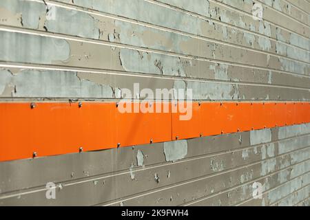 Vecchia parete con striscia arancione. Dettagli dell'edificio. Trama della superficie diagonalmente. Vernice rovinata. Foto Stock