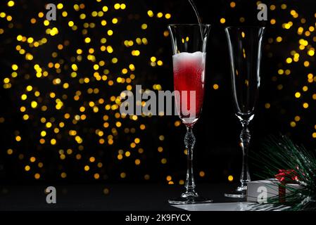 L'inizio di un Capodanno o di una festa di Natale. Versare lo champagne in un bicchiere senza persone. Il processo di versamento dello champagne. Foto Stock