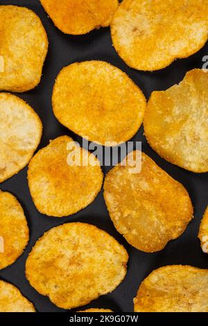Deliziose patatine croccanti con spezie su sfondo nero, vista dall'alto Foto Stock