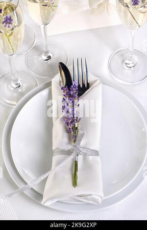 Tavolo da pranzo in stile provenzale, con Champagne lavanda, tovagliolo piegato con posate, decorato con lavanda fresca. Particolare della cena di nozze. Wedd Foto Stock