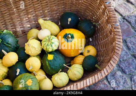 Piccole zucche in paniere tessuto per la vendita sul mercato degli agricoltori come decorazione in autunno. Foto Stock