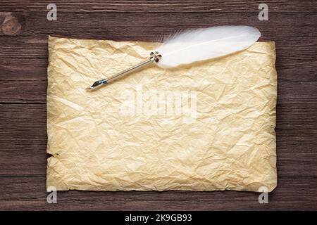 Piuma bianca e carta vecchia su superficie di legno Foto Stock