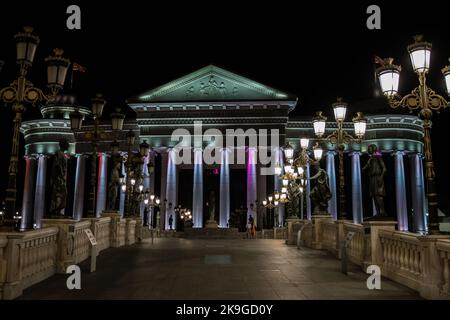 Statue che decorano il Ponte delle civiltà, di fronte al Museo Archeologico di Skopje, Macedonia settentrionale. Di notte con lampioni che illuminano il ponte. Foto Stock