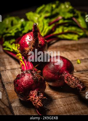 Vista ravvicinata verticale delle barbabietole rosse fresche e organiche sulla superficie di legno Foto Stock