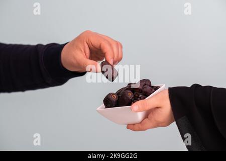 donna musulmana moderna che tiene un piatto pieno di datteri dolci sul tempo di iftar in ramadan kareem islamico sano concetto di cibo Foto Stock