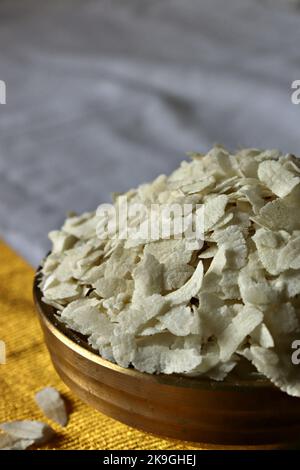 Primo piano di poha crudo/riso battuto/riso appiattito in un Uruli di ottone/nave Foto Stock