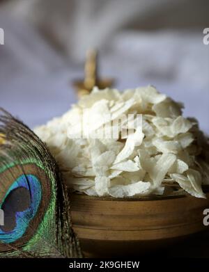 Primo piano di poha crudo/riso battuto/riso appiattito/lampada ad olio di ottone/piuma di pavone-Krishna Janmashtami Foto Stock