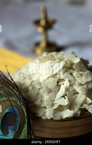 Primo piano di poha crudo/riso battuto/riso appiattito/lampada ad olio di ottone/piuma di pavone-Krishna Janmashtami Foto Stock