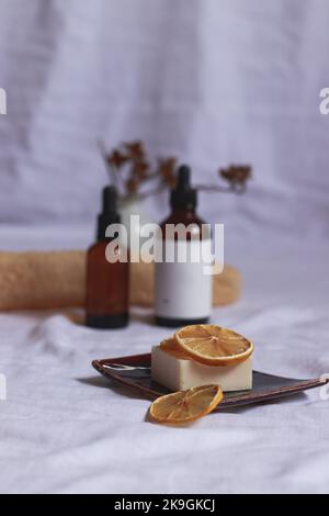 Bottiglie di olio essenziale e sapone vegano biologico con fettine di limone essiccato per mostrare il concetto di spa, bellezza e benessere Foto Stock