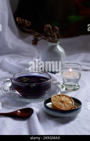 Shot verticale di bottiglie di olio essenziale, fettine di limone essiccate e una candela da tè per un'accogliente atmosfera autunnale spa Foto Stock